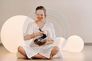 Portrait of a female yoga teacher playing a Tibetan bowl or singing a bell in the gym during a yoga retreat