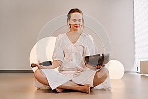 Portrait of a female yoga teacher playing a Tibetan bowl or singing a bell in the gym during a yoga retreat