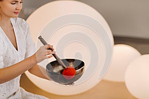 Portrait of a female yoga teacher playing a Tibetan bowl or singing a bell in the gym during a yoga retreat