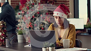 Portrait of festive employee using laptop in office with seasonal decorations