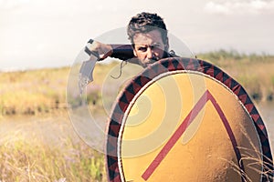 Portrait of fighting ancient warrior in armor with sword and shield