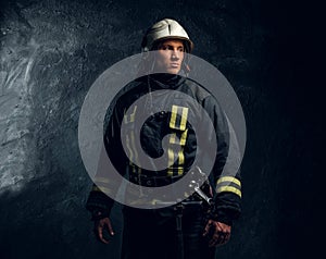 Portrait of firefighter dressed in uniform and safety helmet looking sideways with a confident look