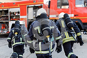 Portrait of firefighter in uniform in front of fire engine machine and fireman team