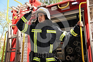 Portrait of firefighter in uniform and helmet near fire truck outdoors