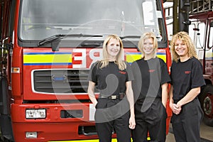 Portrait of firefighters standing by a fire engine