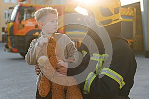 Portrait of a fireman and a little boy with a teddy bear.