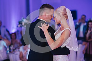 Portrait of first dance of stylish wedding couple. Handsome groom and elegant bride in the restaurant