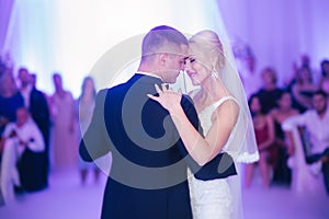 Portrait of first dance of stylish wedding couple. Handsome groom and elegant bride in the restaurant