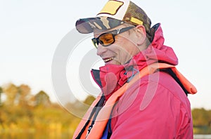Portrait of a fisherman in sunglasses, cap, safety vest.