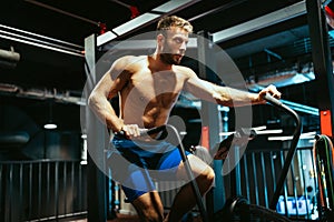 Portrait of fit handsome man workout on a fitness machine at gym