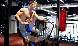 Portrait of fit handsome man workout on a fitness machine at gym