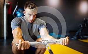 Portrait of fit handsome man workout on a fitness machine at gym