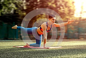 Portrait of fit and sporty young woman doing exercises of stretching, yoga or pilates in the early morning park