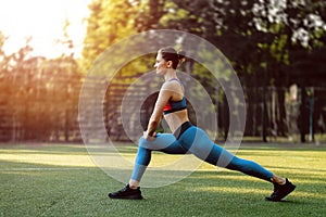 Portrait of fit and sporty young woman doing exercises of stretching, yoga or pilates in the early morning park