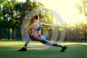 Portrait of fit and sporty young woman doing exercises of stretching, yoga or pilates in the early morning park