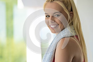 Portrait of Fit woman on exercise bike wiping sweat with towel at the gym