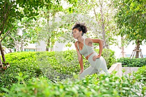 Portrait of fit young female stretching body in outdoor park. Beautiful African woman preparing, practicing, training, sport,