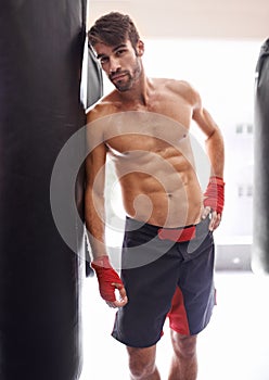 Portrait, fitness and body of fighter man in gym with punching bag for training strong muscles. Exercise, health and