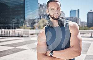 Portrait, fitness and city with a sports man standing arms crossed while listening to music furing his workout. Exercise