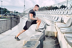 Portrait of fitness, healthy man making stretching after long workout. Running and fitness concept