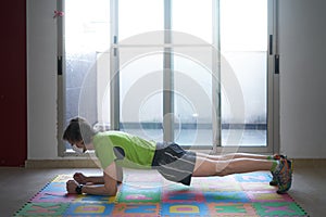 Portrait of a fitness man wearing a surgical mask and doing iron-on mat exercises at home