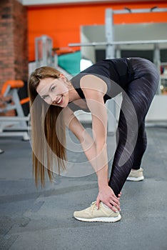 Portrait of fitness woman stretching at gym before workout. Female stretch inner thigh. Sports activity, healthy