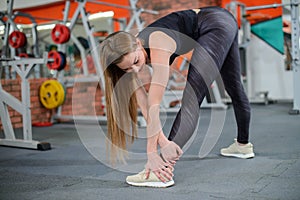 Portrait of fitness woman stretching at gym before workout. Female stretch inner thigh. Sports activity, healthy