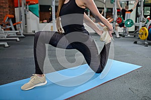 Portrait of fitness woman stretching at gym before workout. Leg stretches. Sports activity, healthy lifestyle.