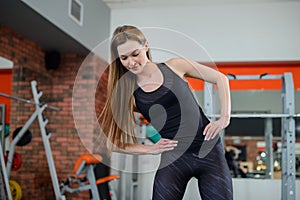 Portrait of fitness woman stretching at gym before workout. Sports activity, healthy lifestyle. Sideways lean exercise.