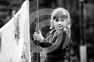 Portrait of five-year girl with clothespin outdoor. Black and white photo.