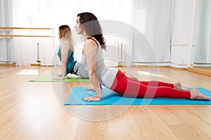 Portrait of flexible yogini doing asana bhujangasana in yoga studio