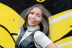 Portrait of a flirtatious playful girl on blurred wall sprayed with graffiti