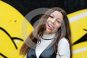 Portrait of a flirtatious playful girl on blurred wall sprayed with graffiti