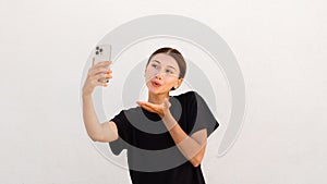 Portrait of flirty young woman sending kiss and taking selfie