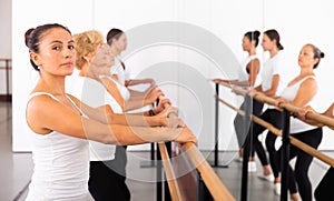 Portrait of a focused latin american woman, doing demi plie near the ballet barre