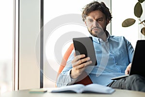 Portrait of focused man using digital tablet and pc