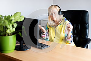 Portrait of focused middle-aged woman wearing headphones watching webinar at office computer