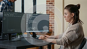 Portrait of focused programer writing code looking at multiple computer screens