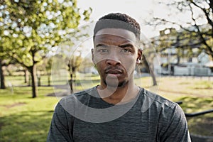 Portrait of focused young black man in sports clothing looking at camera in park
