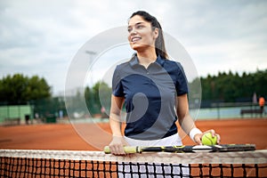 Portrait of forceful woman playing tennis on outdoor tennis court