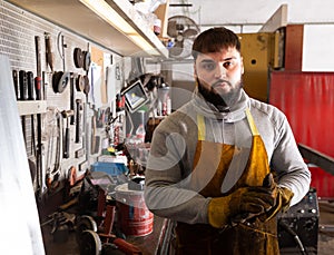 Portrait of foreman in protective gloves and apron standing in workshop