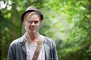 Portrait, forest and man with a smile, adventure and summer with tourism, travelling and happiness. Face, person and guy