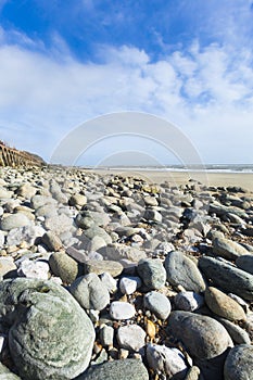 Portrait format wide angle pebble beach and blue sky
