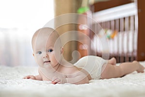 Portrait of four months old baby on the bed in nursery room