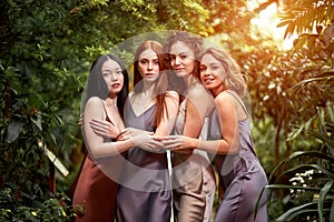 portrait of four sensual ladies in elegant silk dresses in the forest