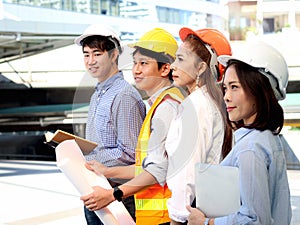 Portrait of four smart young Asian man and woman engineer group, staff worker team wear safety vest and helmet, confidential