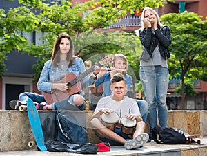 Portrait of four teenagers playing music together outdoors