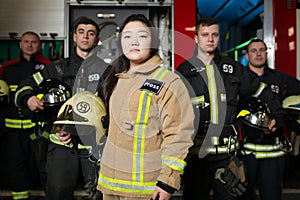 Portrait of four young male and female firefighters on background of fire truck