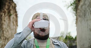 Portrait of FPV pilot standing in a canyon and controlling a drone using goggles