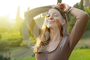 Portrait of free woman breathing clean air in nature. Happy girl with raised arms in bliss. Relaxing, quietness outdoor, wellness